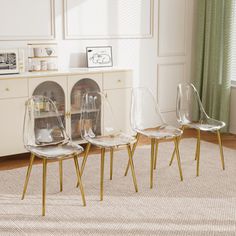 three clear chairs sitting on top of a rug in front of a white cabinet and window