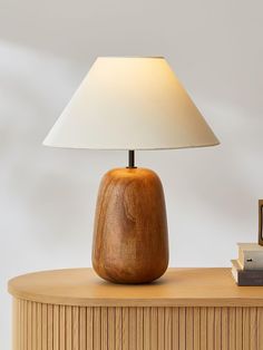 a wooden table with a lamp on top of it next to a stack of books