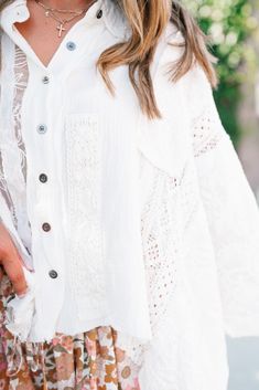 The Lakelyn Lace Ivory Button Up Top is a beautifully crafted, off-white lace and gauze blouse that exudes a romantic, bohemian vibe. The top features a delicate mix of lace and textured fabric, creating a soft and airy look perfect for layering. It has a button-down front with small, dark buttons that add a subtle contrast to the light fabric. The collar is slightly frayed, contributing to its relaxed and effortless style. The sleeves are voluminous and made entirely of intricate lace, adding a White Lace Patchwork Top For Brunch, White Lace Top With Patchwork For Day Out, White Feminine Crochet Top For Brunch, White Lace Trim Top For Brunch, White Crochet Top For Summer Wedding, White Button-up Top For Wedding, Bohemian Lace Blouse For Day Out, Feminine White Blouse With Boho Collar, Bohemian Lace Patchwork Tops For Brunch