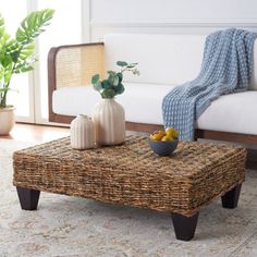 a wicker coffee table sitting on top of a rug next to a white couch