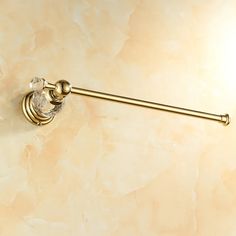 a gold toilet paper holder with a crystal ball on the top and an antique brass finish