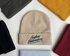 five beanies are laid out on top of each other, with the word custom embroidery