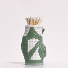 a green and white vase with toothbrushes in it's holder on a table