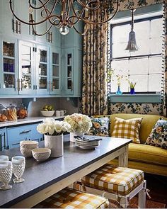 a kitchen with blue cabinets, yellow chairs and a chandelier hanging from the ceiling