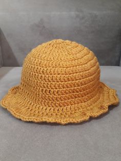 a yellow crocheted hat sitting on top of a white table next to a gray wall