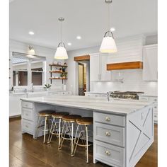 a kitchen island with stools in the middle and two lights hanging over it,