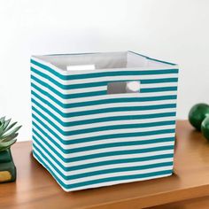 a blue and white striped box sitting on top of a wooden table next to succulents