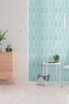 a room with a table, chair and plant on the floor in front of a blue tiled wall