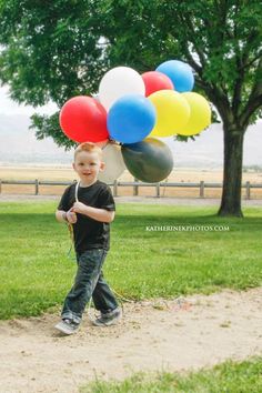 a young boy holding balloons in his hand