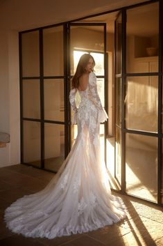 a woman in a wedding dress is standing by an open door with her back to the camera