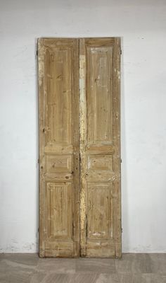 an old pair of wooden doors sitting on top of a hard wood floor next to a white wall