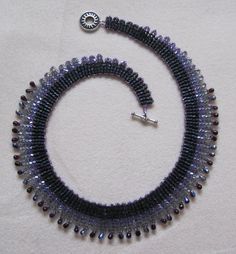 a black and silver beaded necklace on a white surface