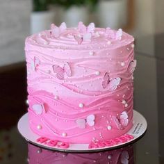 a pink cake with white butterflies on it