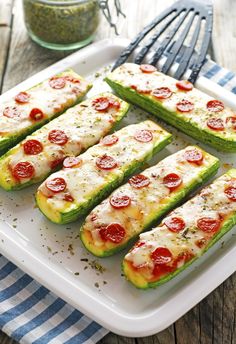 zucchini stuffed with pepperoni and cheese on a white plate next to a fork