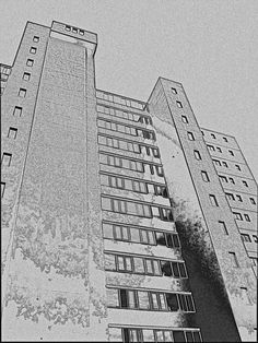 black and white photograph of two tall buildings with windows on each floor in front of a cloudy sky