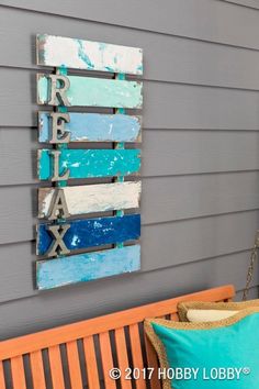 a wooden sign hanging on the side of a gray wall next to a blue and white pillow