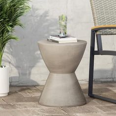 an outdoor table with a potted plant next to it and a chair in the background