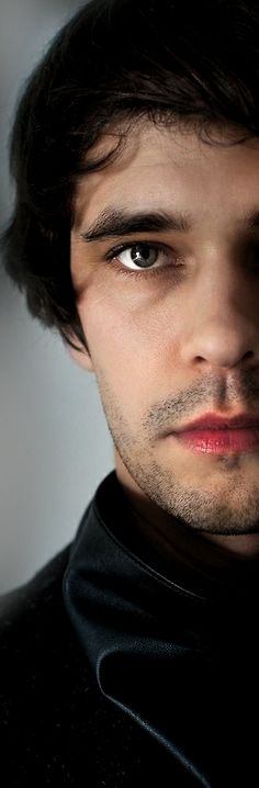 a close up of a person wearing a black shirt and looking at the camera with a serious look on his face