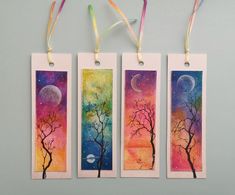 three bookmarks with trees painted on them hanging from strings, one has a moon and the other is a tree