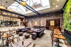 the interior of a restaurant with wooden tables and leather couches in front of a bar