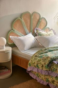 a bed with white pillows and green headboard next to a lamp on a table