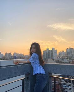 a woman standing on top of a roof next to a tall building with buildings in the background