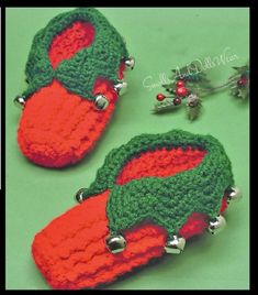 two crocheted red and green christmas mitts with bells on them sitting next to each other