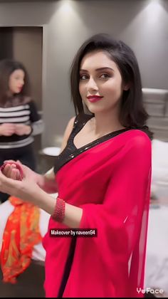 a woman in a pink sari is holding her hand out to the camera and smiling