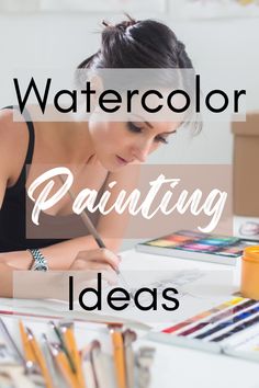 a woman sitting at a table with watercolor paints and pencils in front of her