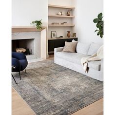 a living room with a white couch, fireplace and book shelf on the wall next to it