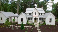 a large white house surrounded by trees and rocks