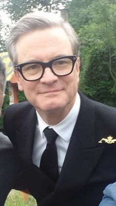 two men in suits and ties are posing for a photo together with trees in the background