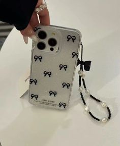 a person is holding an iphone case with bows on it and pearls hanging from the back