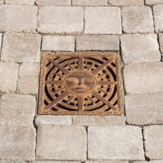 a manhole cover with a face on it in the middle of a brick walkway