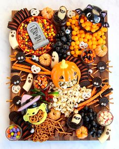 a wooden tray topped with lots of halloween treats and candies on top of it