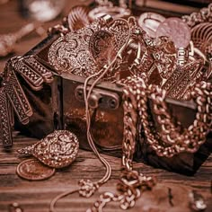 a box filled with lots of jewelry on top of a wooden table next to other items