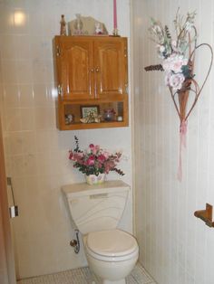 a white toilet sitting in a bathroom next to a wooden cabinet with flowers on it