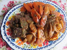 a plate full of meat and vegetables on a floral table cloth with flowers around it