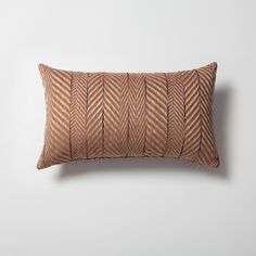 an orange and white striped pillow on a white wall