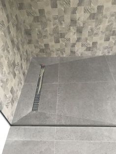 a tiled shower stall with a grate in the floor