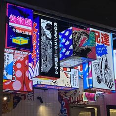 an array of colorful posters hang from the ceiling above a tiled wall in a restaurant