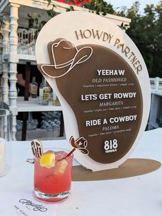 a drink sitting on top of a table next to a sign that says, yeehaw let's get rowdy ride a cowboy