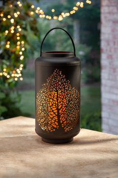 a lit candle sitting on top of a wooden table next to a tree and lights