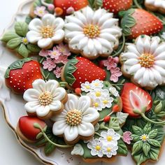 decorated cookies on a plate with flowers and strawberries