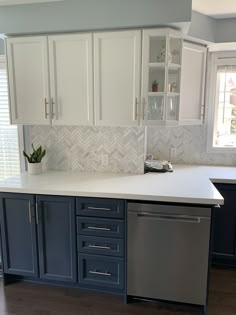 a kitchen with blue cabinets and white counter tops is pictured in this image, the dishwasher has been left open