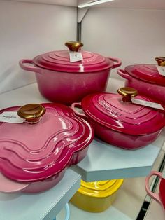 pink pots and pans are on display in a room with other items behind them