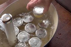 a person is pouring water into a pan with ice cubes and cans in it