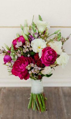 a bouquet of flowers sitting on top of a wooden table next to a white wall