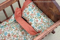 a wooden crib with a pillow on top of it and an orange cushion in the middle