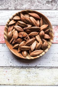 a wooden bowl filled with nuts sitting on top of a table